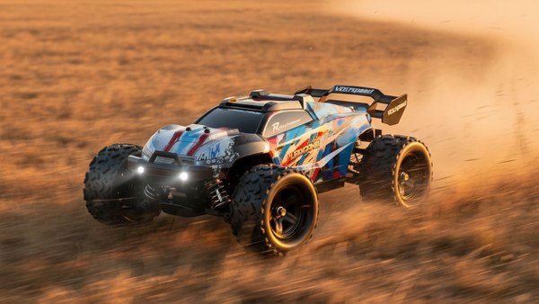 Hurricane Monster Truck bleu en pleine vitesse dans champ d'herbe sèche au coucher de soleil