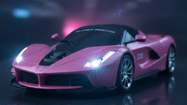 Détail aérodynamique du capot noir et des prises d'air latérales de la voiture rose